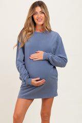 woman wearing a blue oversized sweatshirt dress and holding her baby bump, maternity wear