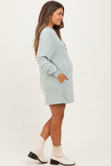 woman wearing a light green long sleeve maternity dress with pockets and a visible baby bump