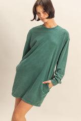 woman wearing a green oversized sweatshirt dress with long sleeves and side pockets