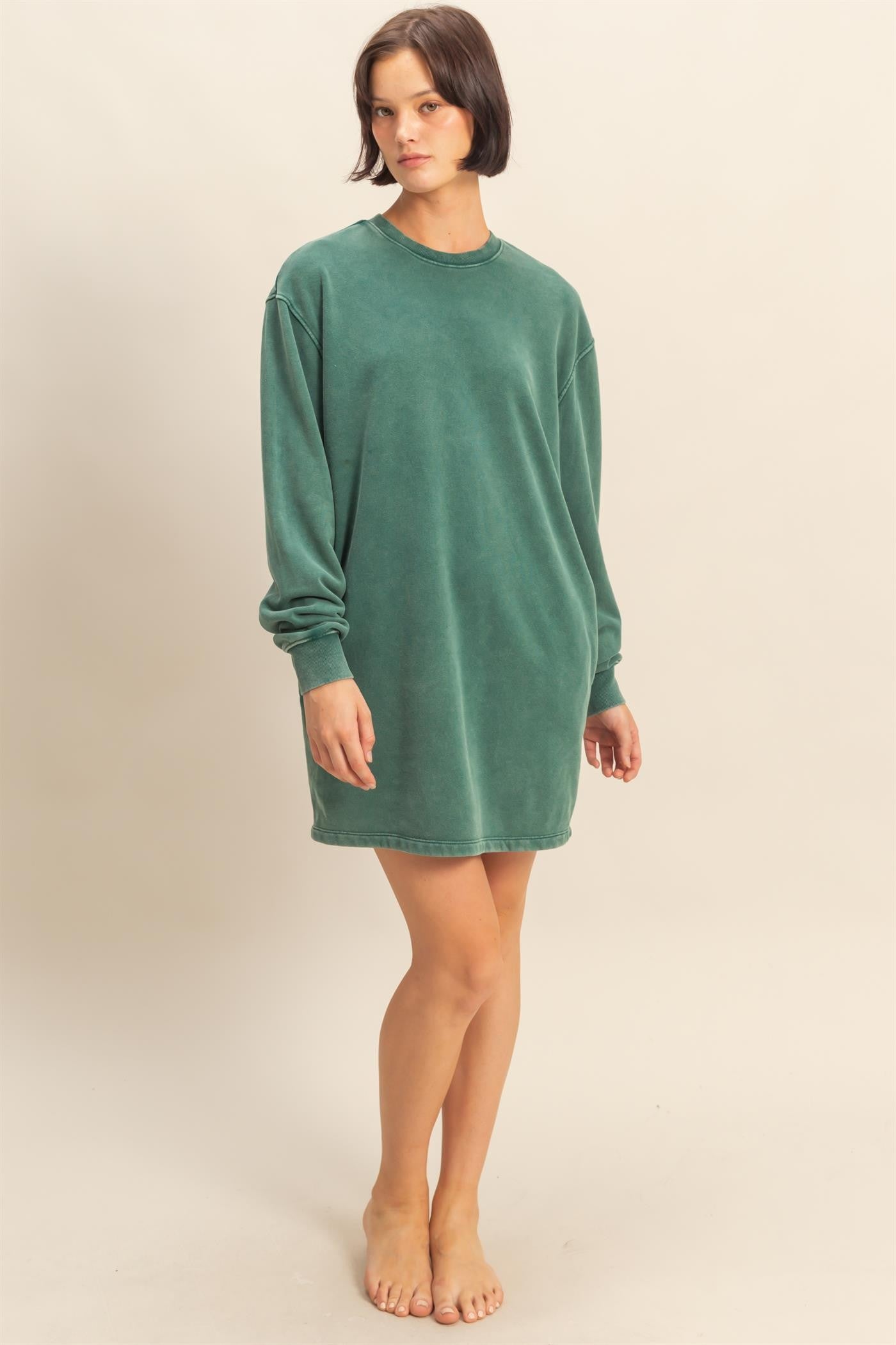woman wearing a loose-fitting green sweatshirt dress with long sleeves and a round neckline