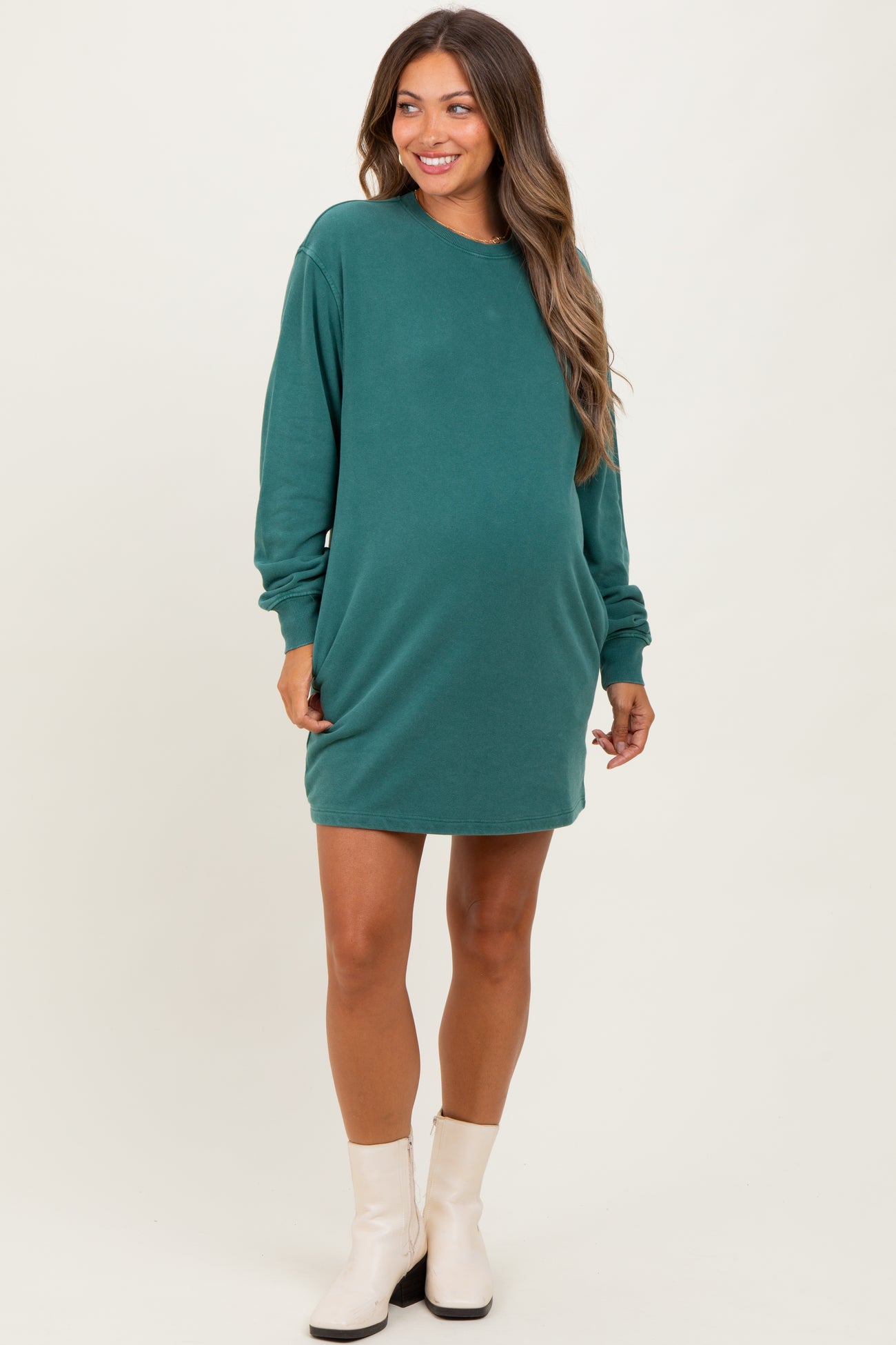 woman wearing a dark green maternity sweatshirt dress with long sleeves and a visible baby bump