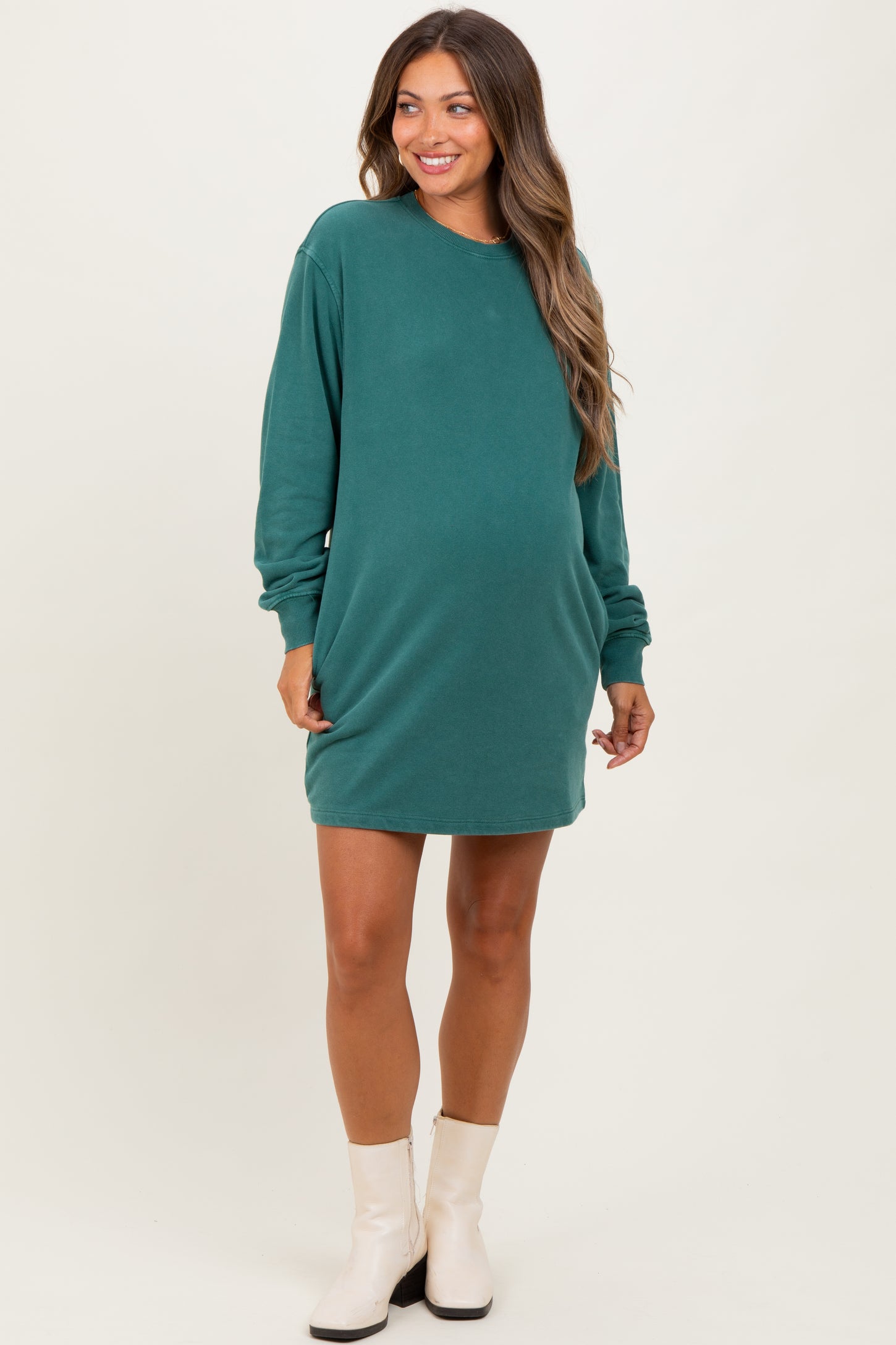 woman wearing a dark green maternity sweatshirt dress with long sleeves and a visible baby bump