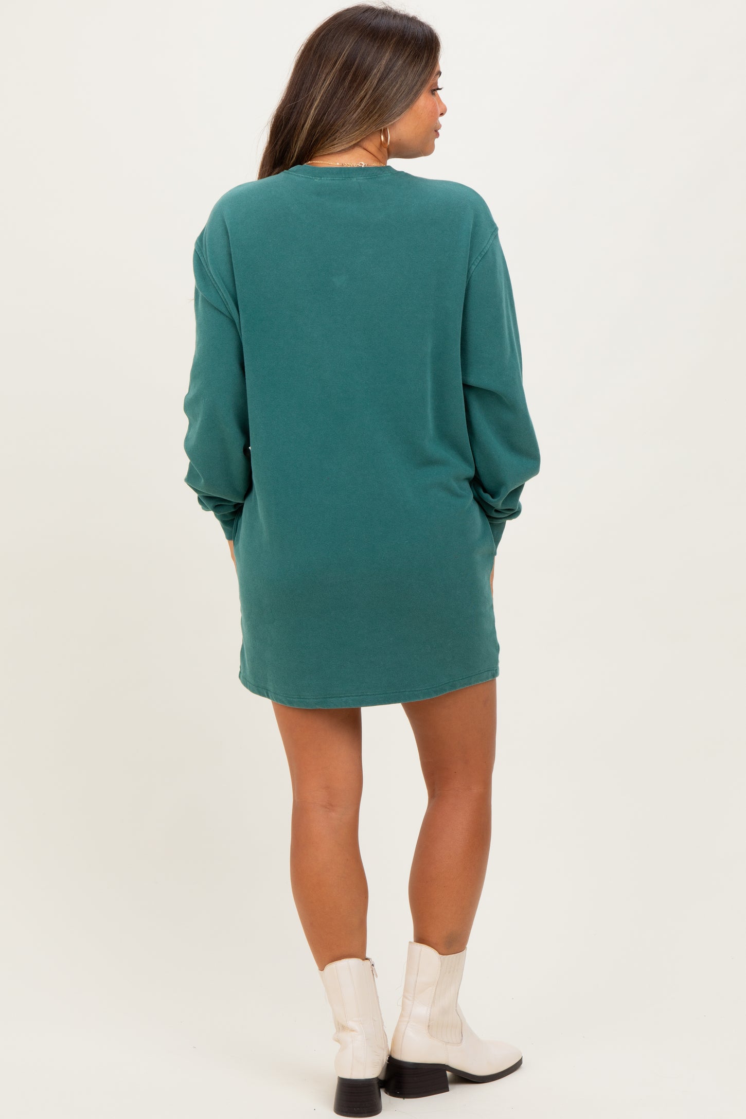 woman wearing a green maternity sweatshirt dress, showing a relaxed fit and long sleeves from the back