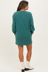 woman wearing a green maternity sweatshirt dress, showing a relaxed fit and long sleeves from the back