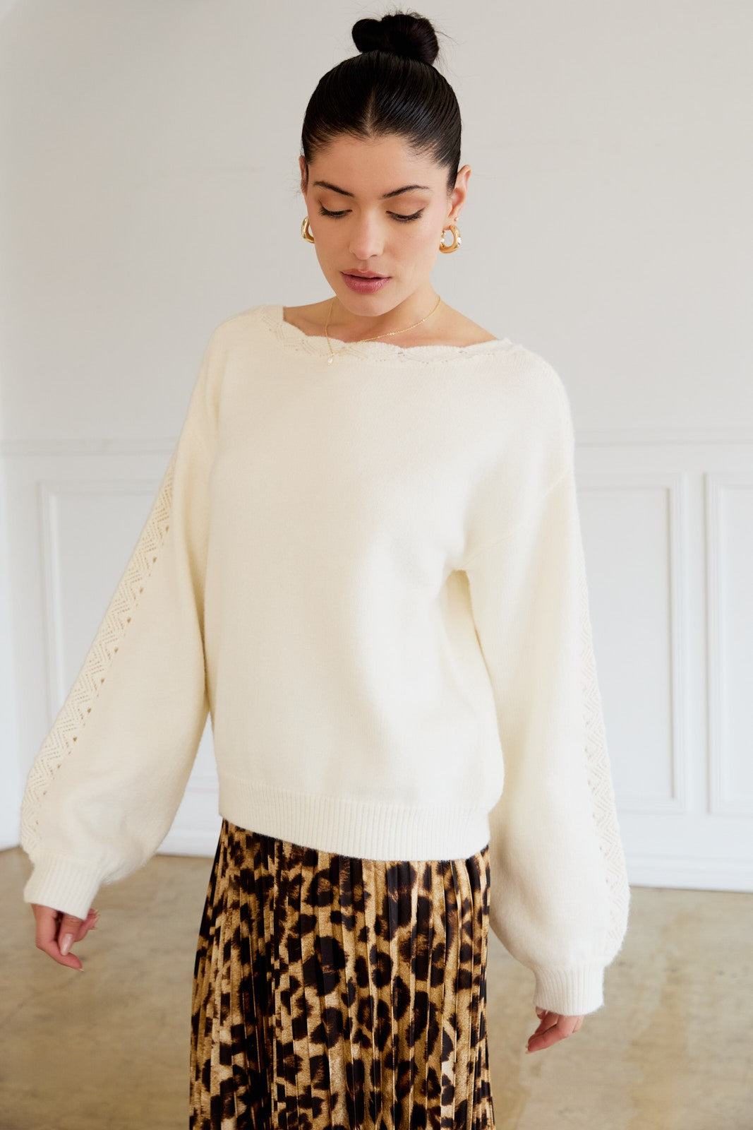 woman wearing a cream oversized sweater with lace details on sleeves and a leopard print midi skirt