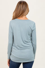 woman wearing a light blue long sleeve maternity top, viewed from the back