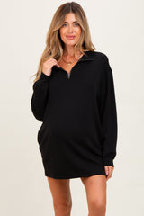 woman wearing a black maternity pullover dress with a half-zip collar and long sleeves, showcasing a baby bump