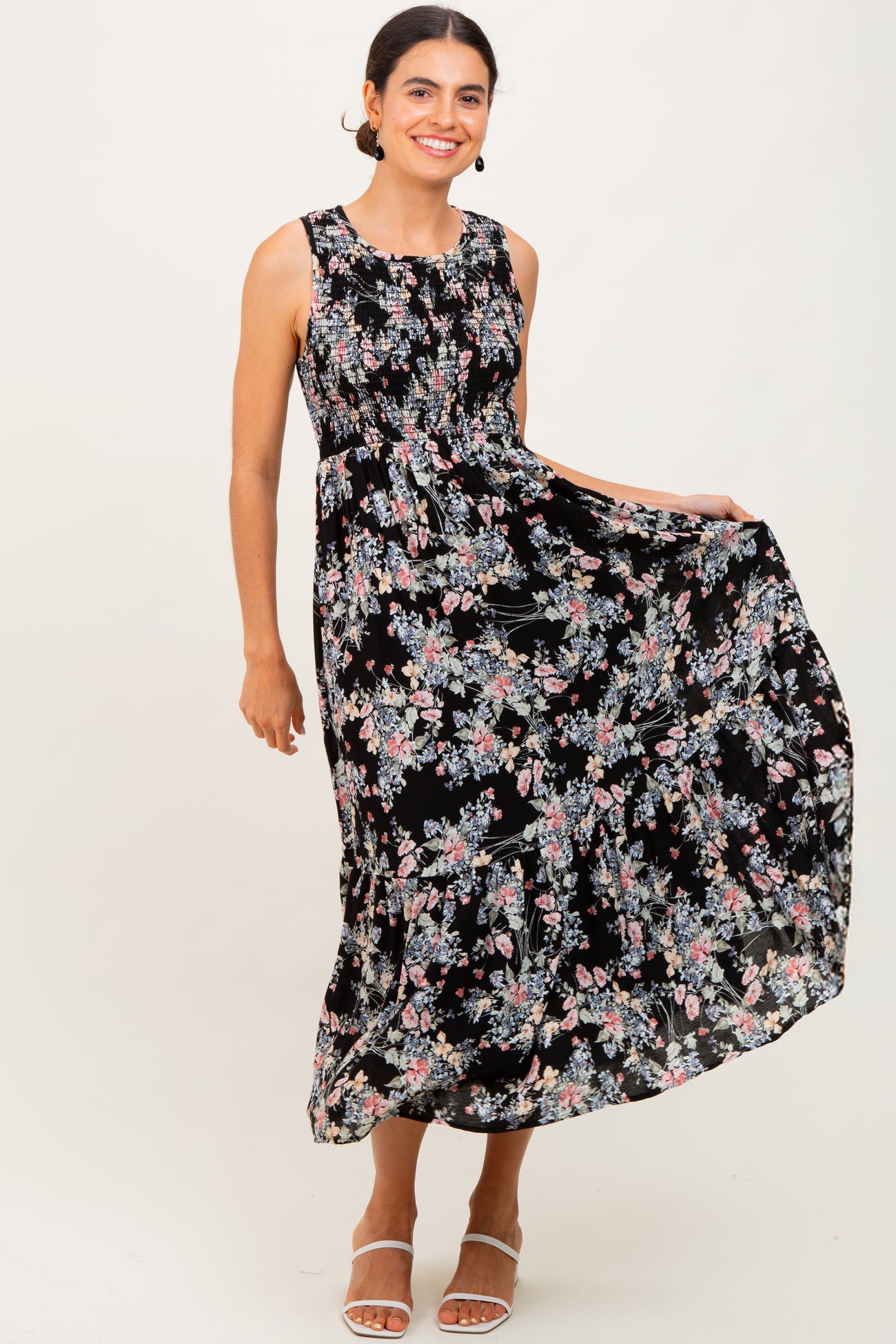 woman wearing a black floral maxi dress with a fitted bodice and flowy skirt, smiling and posing
