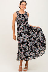 woman wearing a black floral maxi dress with a fitted bodice and flowy skirt, smiling and posing