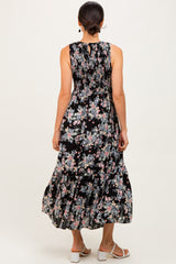 woman wearing a black floral maxi dress with a smocked waist and a flowy skirt, showing the back view