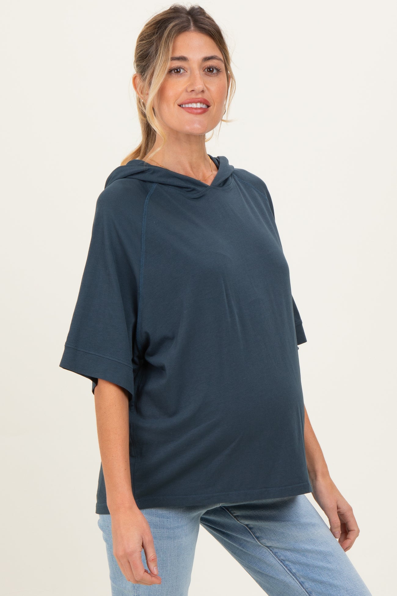 woman wearing a navy blue maternity hoodie with a loose fit and short sleeves, showcasing her baby bump