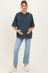 woman wearing a dark blue short sleeve maternity hoodie and holding her baby bump with light wash jeans