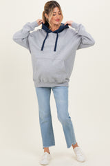 woman wearing a gray maternity hoodie with navy accents and front pocket, paired with light blue jeans and white sneakers