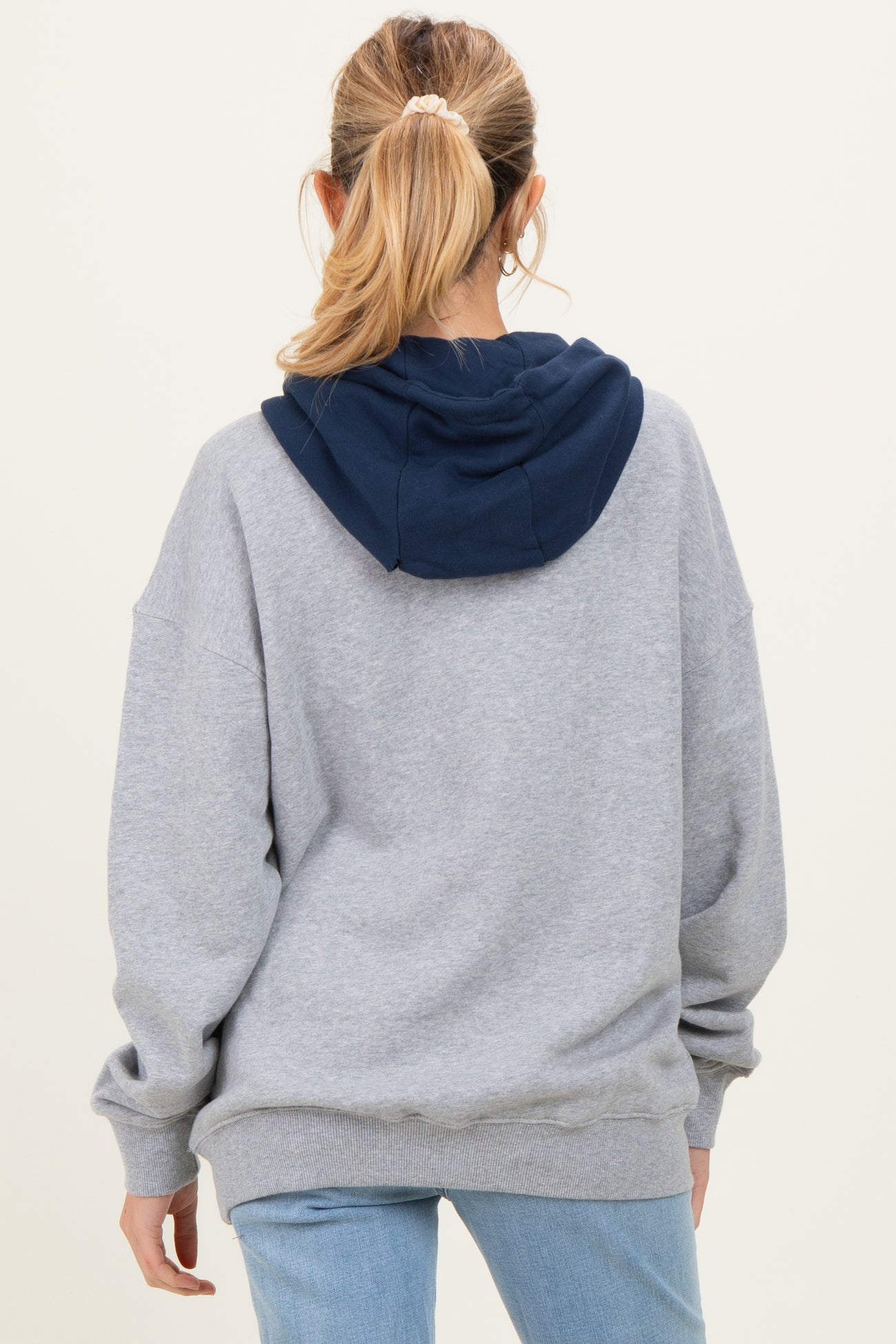 woman wearing a gray maternity hoodie with a navy blue hood, shown from the back