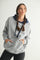 woman wearing a gray oversized hoodie with a navy blue hood and pockets, styled with black leggings