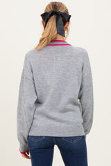 woman wearing a gray maternity sweater with pink detailing, styled with her hair in a ponytail and a black bow