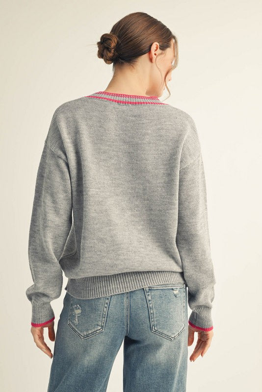 woman wearing a gray oversized sweater with pink detailing, shown from the back with light blue distressed jeans