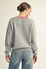 woman wearing a gray oversized sweater with pink detailing, shown from the back with light blue distressed jeans