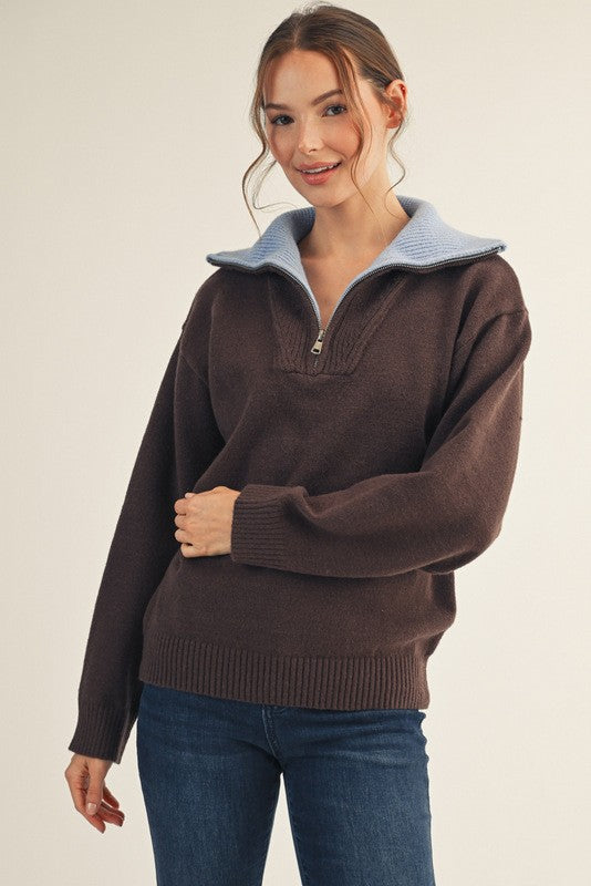 woman wearing a brown zip-up pullover sweater with a light blue collar and casual jeans