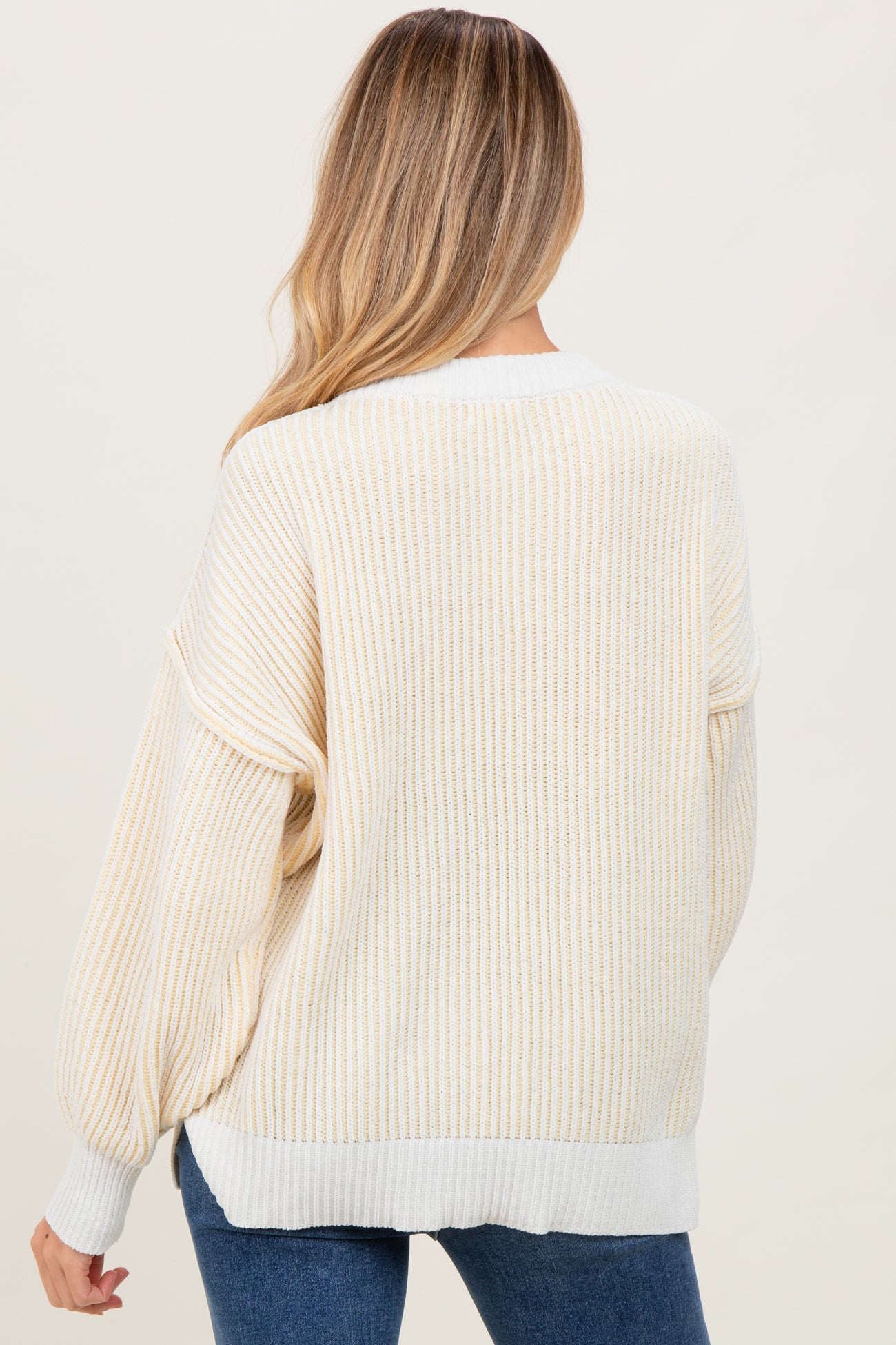 woman wearing a cream and gold striped oversized maternity sweater, viewed from the back with loose sleeves