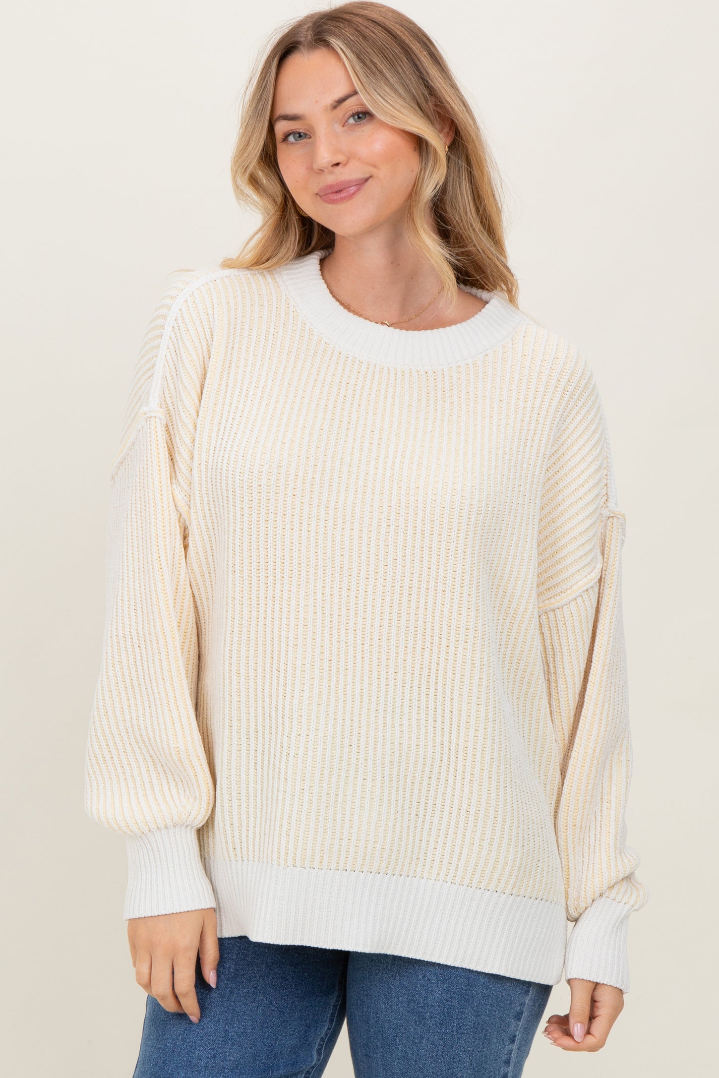 woman wearing a cream and gold striped oversized sweater with balloon sleeves and a relaxed fit