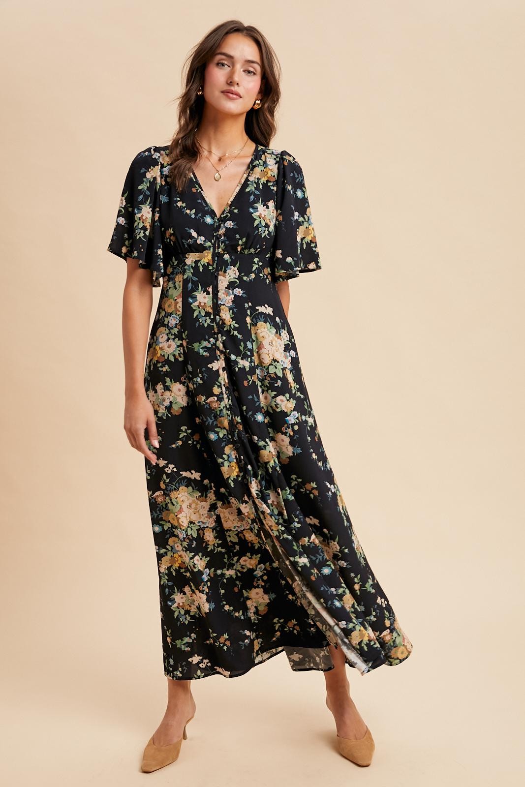 woman wearing a black floral maxi dress with short sleeves and a button-down front, styled with beige flats