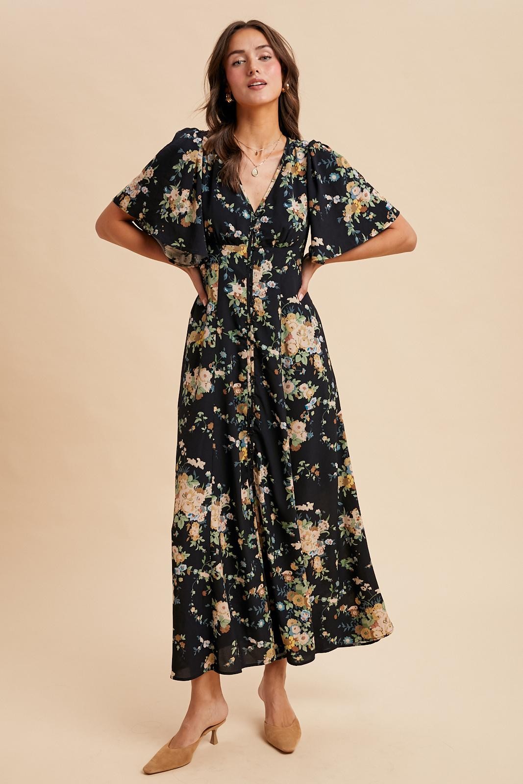 woman wearing a black floral maxi dress with short flutter sleeves and button details
