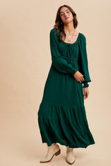 woman wearing a dark green long sleeve maxi dress with tiered detailing and a gathered neckline