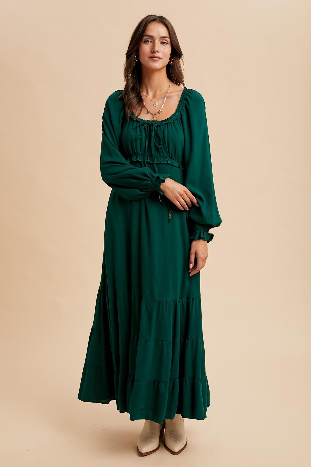woman wearing a long green tiered maxi dress with puff sleeves and a drawstring neckline