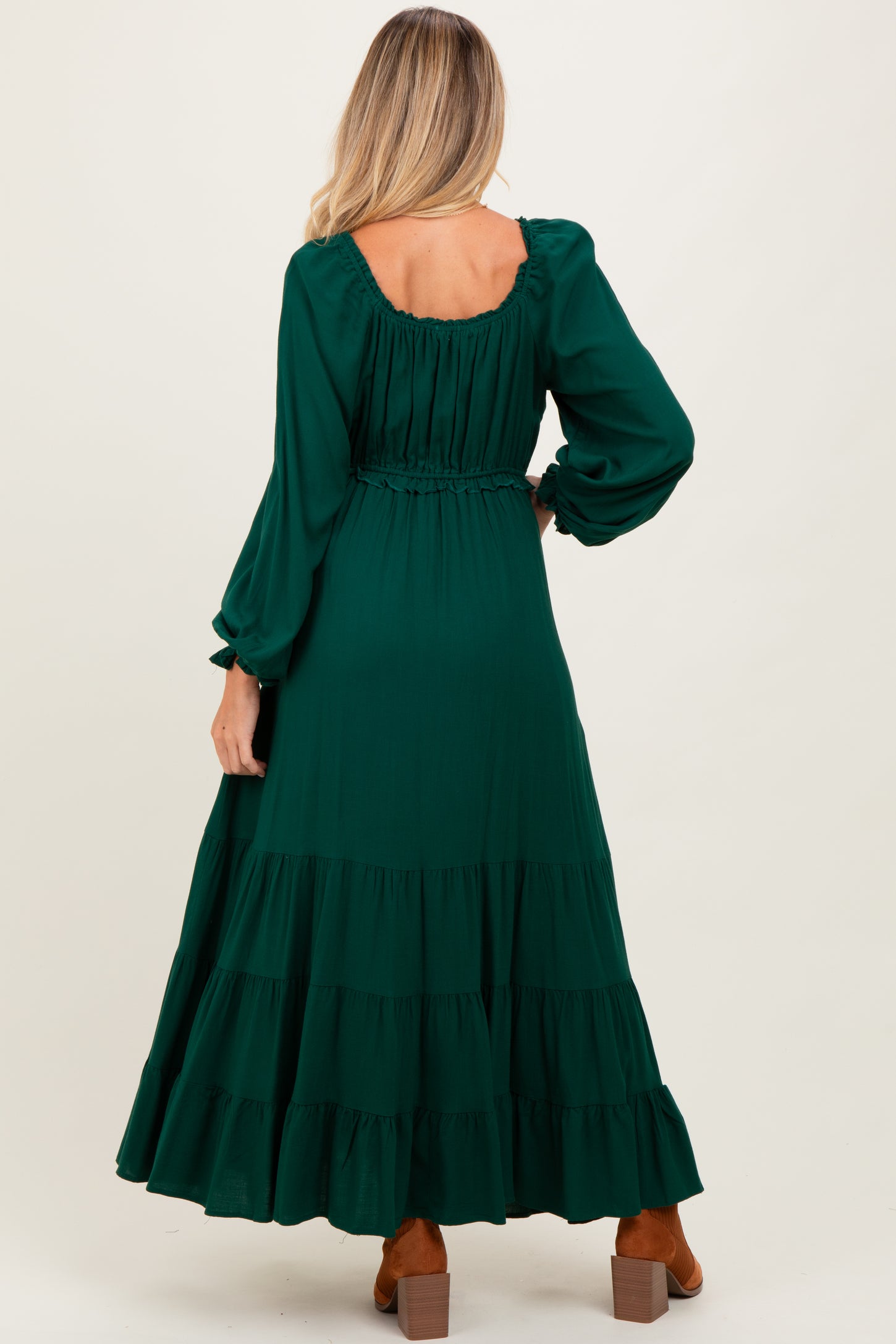 woman wearing a green tiered maternity dress with long sleeves and an elastic waist, showing the back view