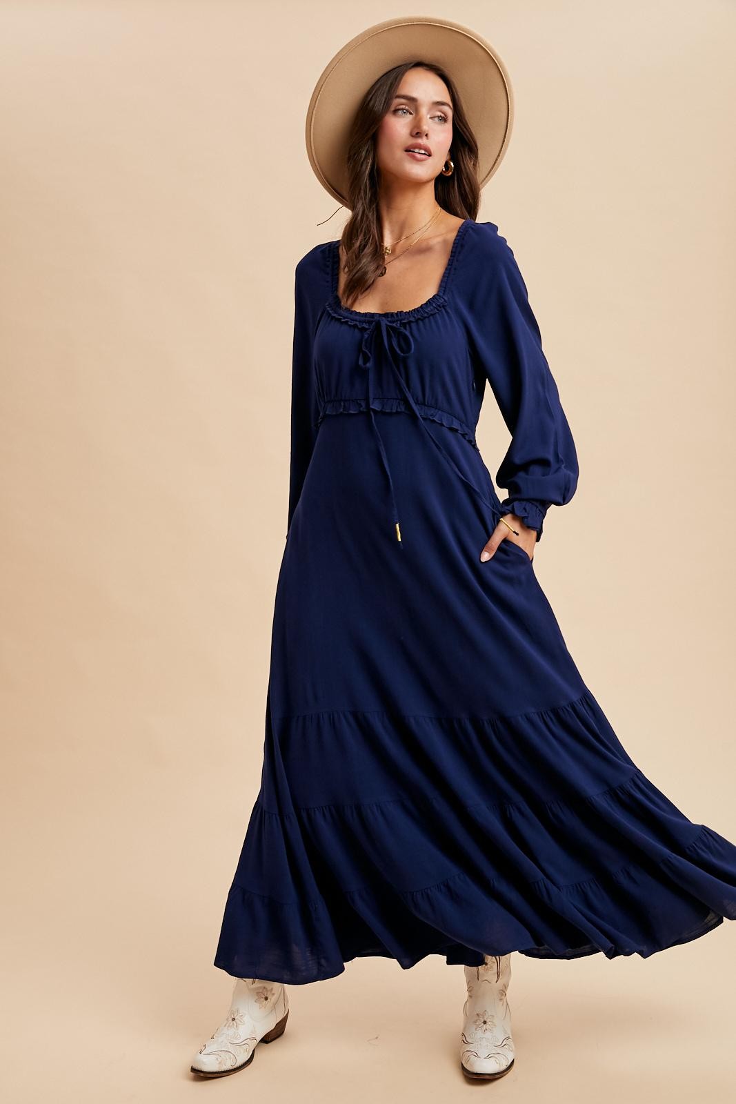 woman wearing a navy blue long sleeve maxi dress with a tie front detail and a wide-brimmed hat