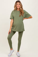 woman wearing an olive green maternity t-shirt and matching leggings, holding her baby bump