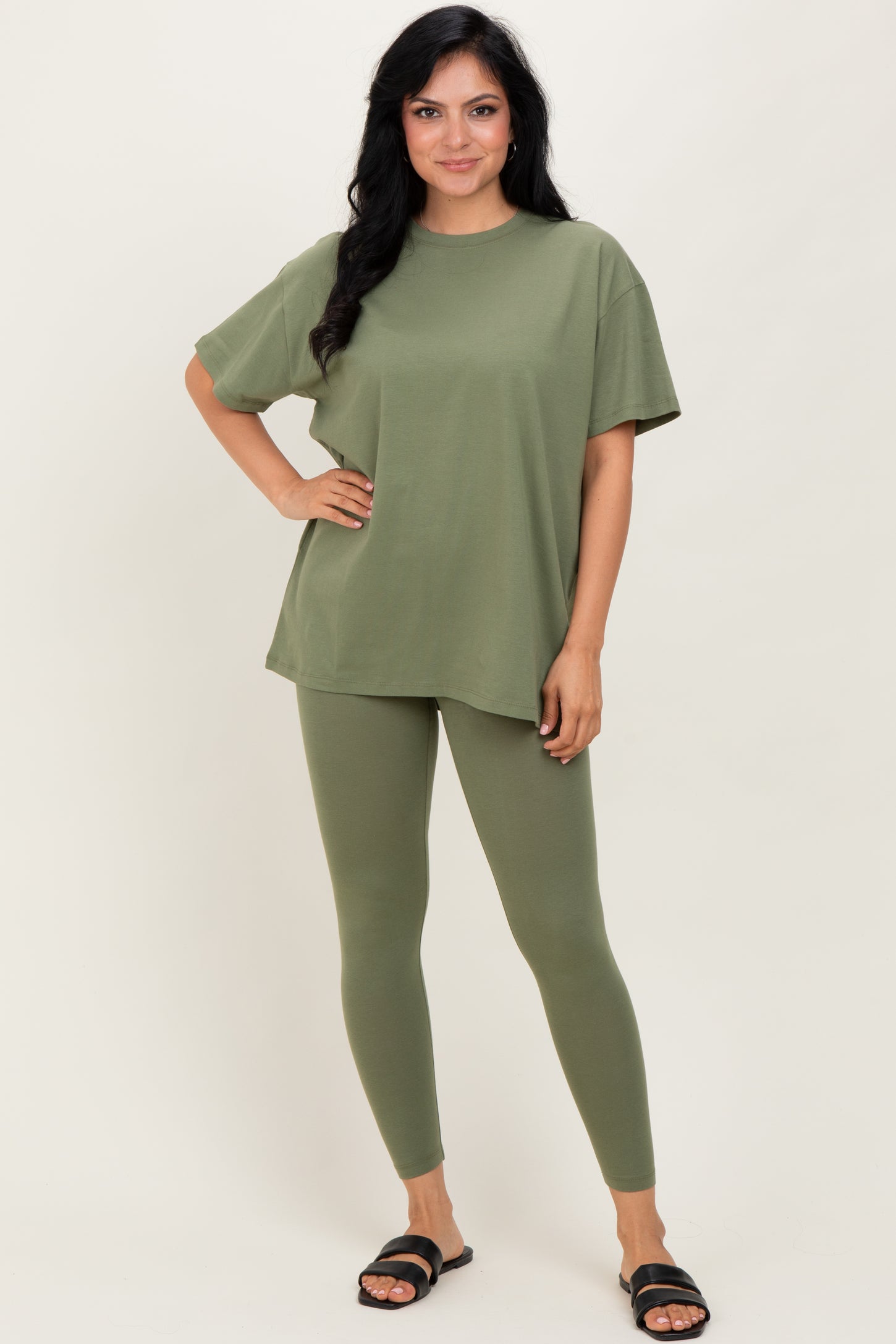 woman wearing an olive green oversized t-shirt and matching leggings, standing with one hand on her hip