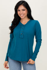 woman wearing a teal long sleeve henley top with button details and a relaxed fit