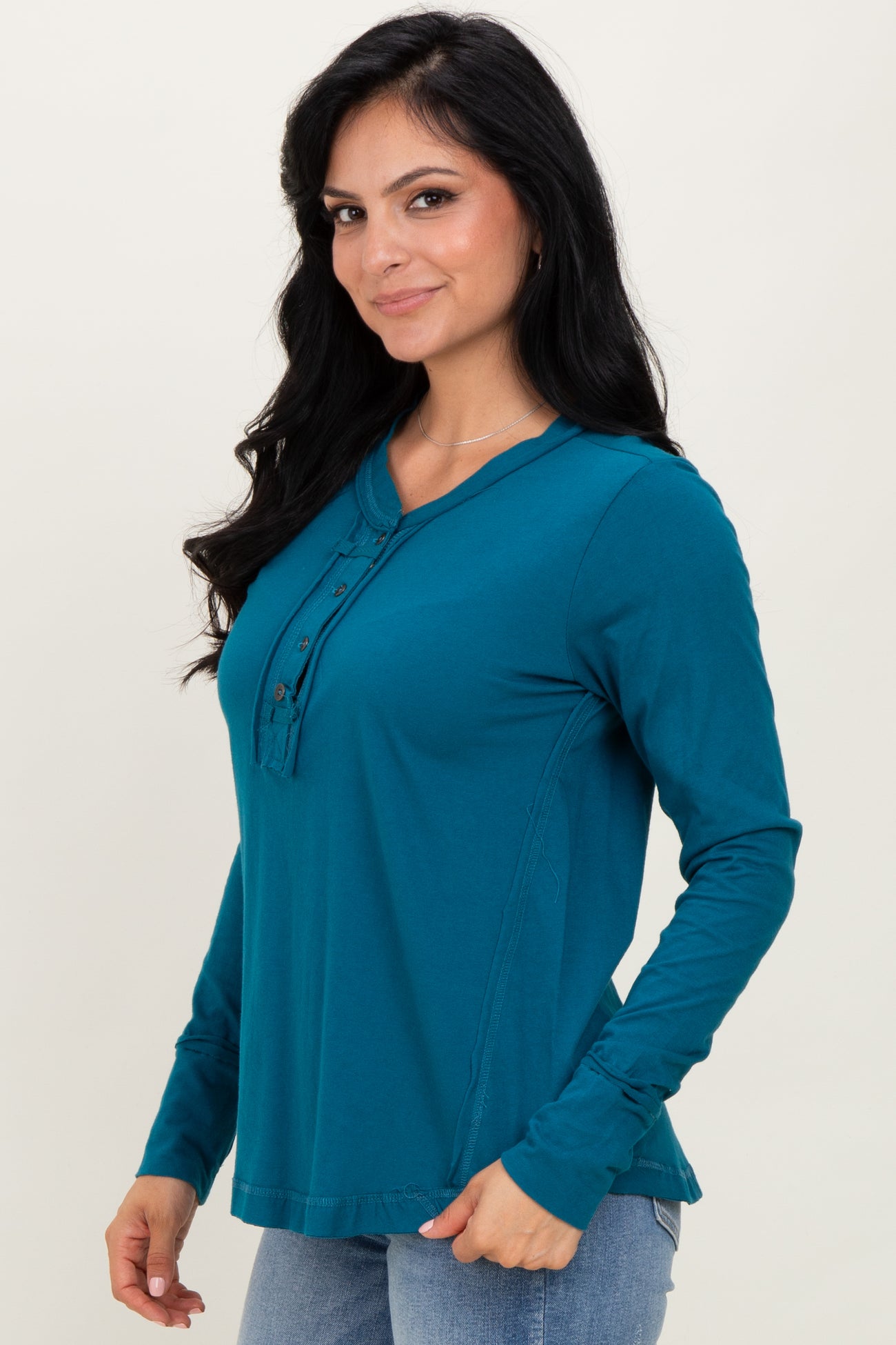 woman wearing a teal long sleeve henley top with button details and a relaxed fit