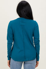 woman wearing a teal long sleeve top with a back seam detail, styled with light blue jeans