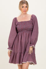 woman wearing a red and blue checked puff sleeve mini dress with a smocked bodice and ruffled hemline