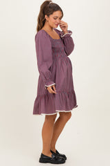 woman wearing a patterned maternity dress with smocked bodice and ruffled hem, showcasing her baby bump