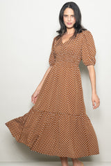 woman wearing a brown polka dot maxi dress with a fitted bodice and puff sleeves, smiling while posing