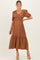 woman wearing a brown polka dot maternity maxi dress with puff sleeves and a tiered hem, showcasing her baby bump