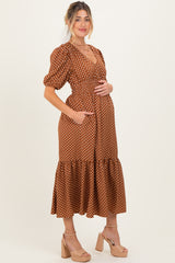 woman wearing a brown polka dot maternity dress with puff sleeves and a ruffled hem, holding her baby bump