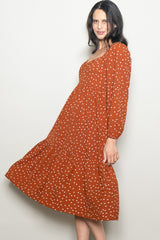 woman wearing a rust colored polka dot long sleeve dress with a tiered skirt