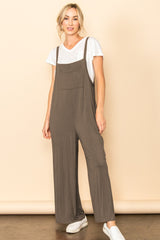 woman wearing a brown sleeveless jumpsuit over a white t-shirt with a front pocket and white sneakers