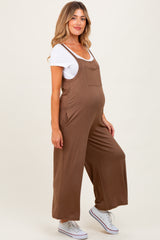woman wearing a brown maternity jumpsuit with side pockets and a white t-shirt underneath, showcasing a baby bump