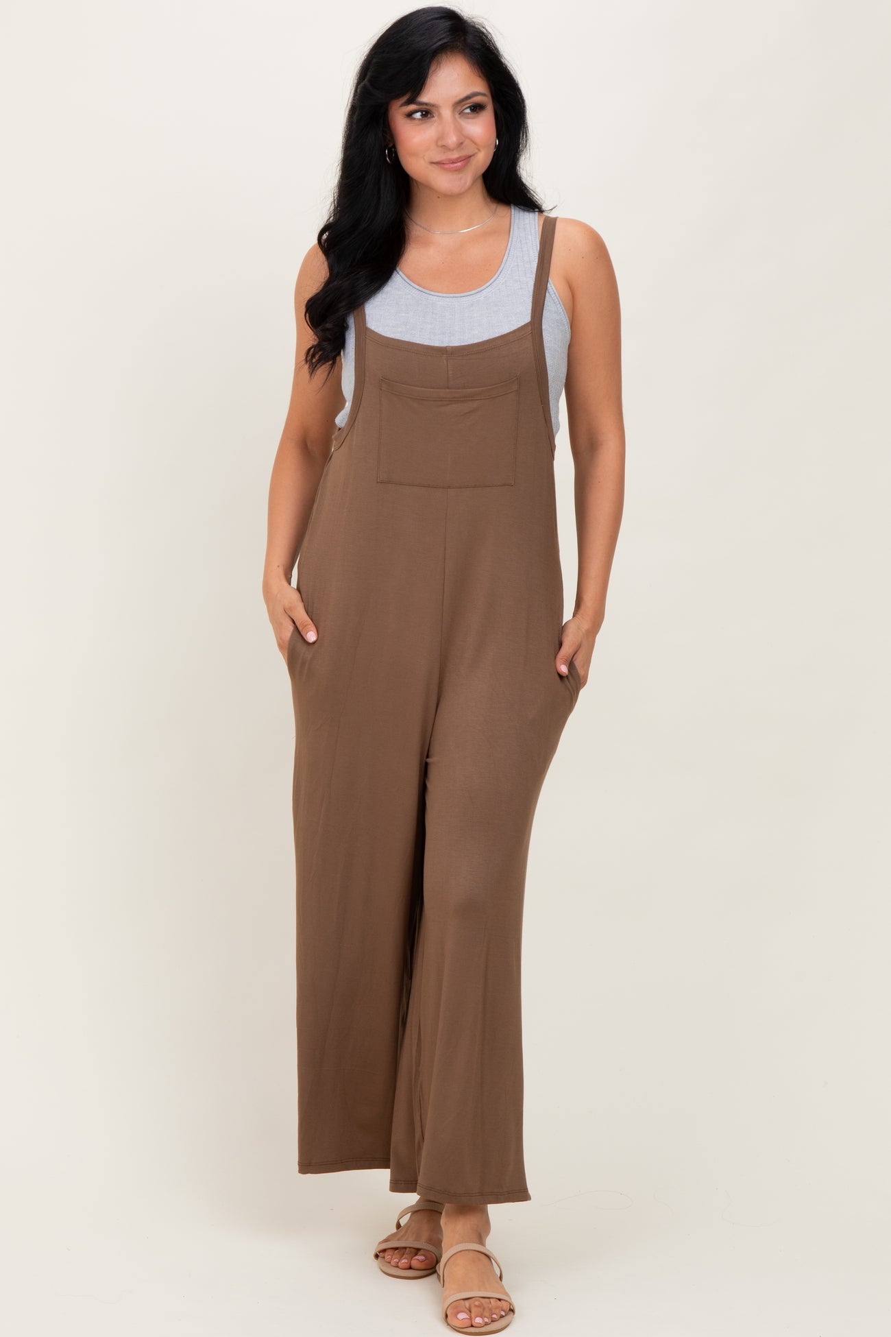 woman wearing a brown sleeveless jumpsuit with wide legs and front pockets