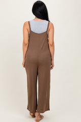 woman wearing a brown backless jumpsuit with a loose fit and wide legs, showing a gray tank top underneath