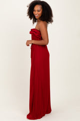 woman wearing a strapless red maxi dress with ruffled detailing and a flowing design