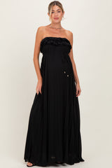 woman wearing a black strapless maternity maxi dress with ruffle detail and a flowing pleated skirt, showing baby bump