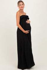 woman wearing a black strapless maternity maxi dress with ruffle detailing and holding her baby bump