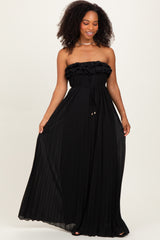 woman wearing a black strapless maxi dress with ruffle details and a tie waist
